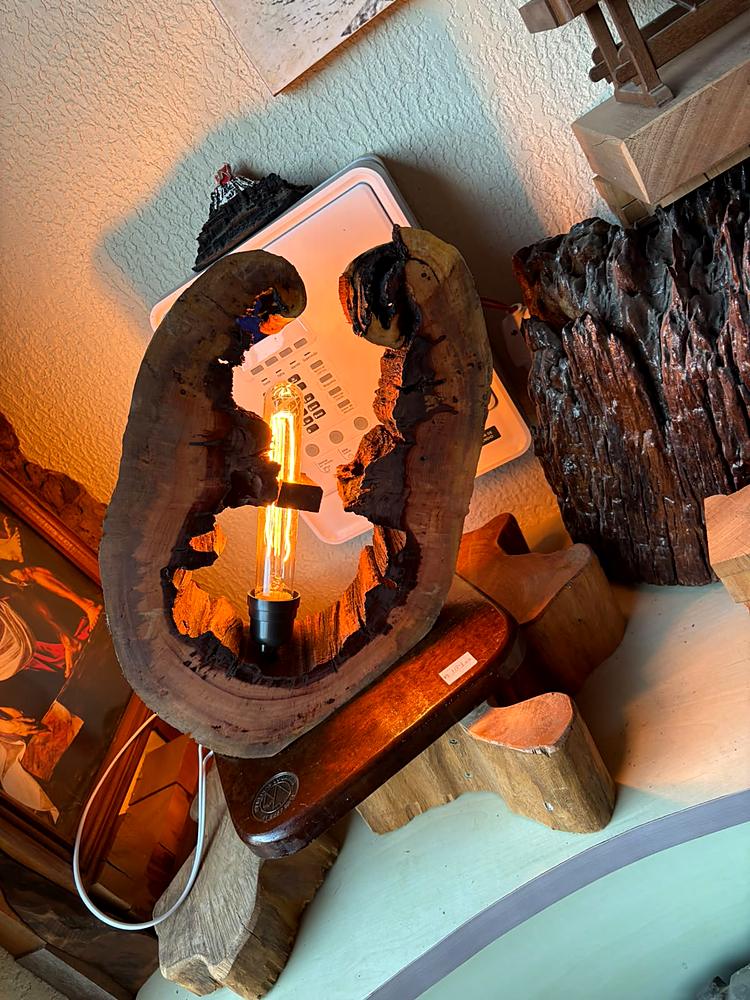 Luminária de tronco escavado acesa, iluminando a parede ao redor